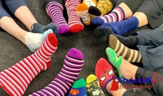 A circle of feet wearing colorful and mismatched socks on a carpet.